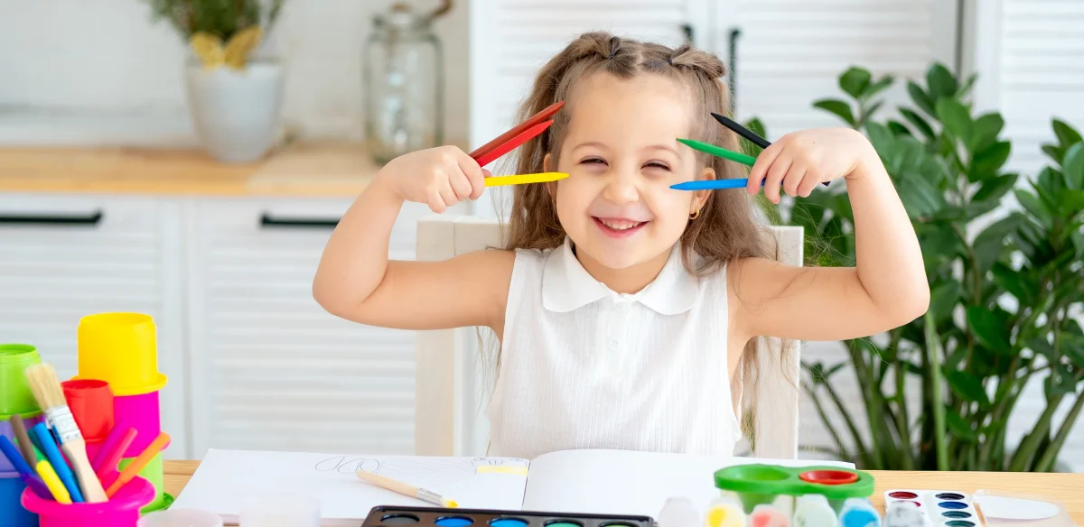 Kindergarten student smiling holding her crayons
